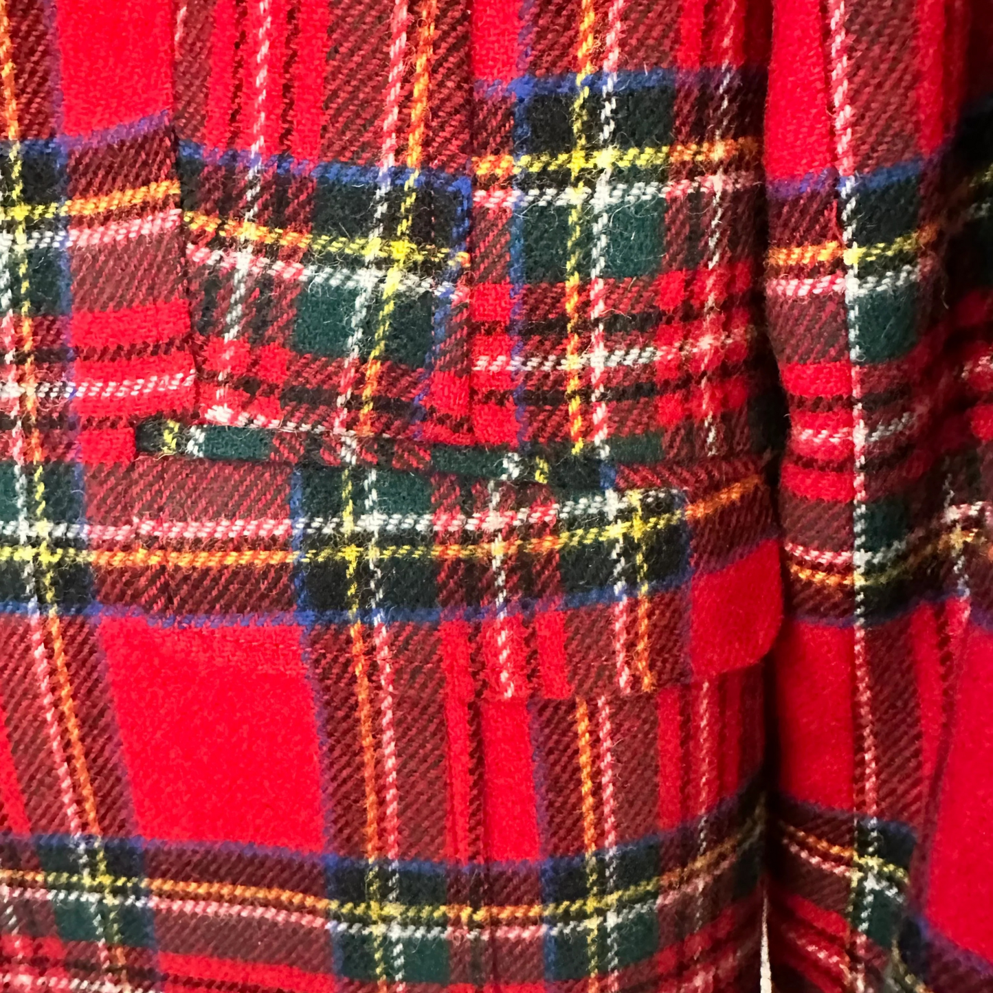 Close-up of red plaid fabric with a pattern of black, yellow, and green lines.