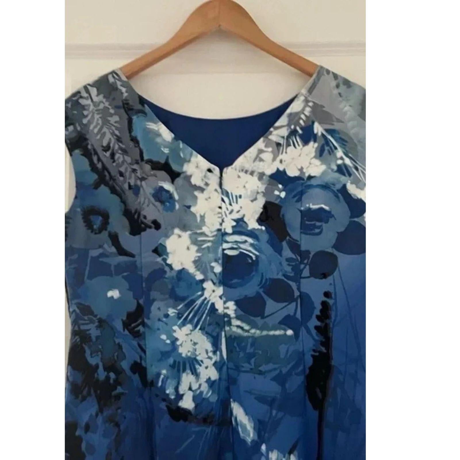 Up close photo of the upper back of Blue floral patterned dress on a hanger against a white wall