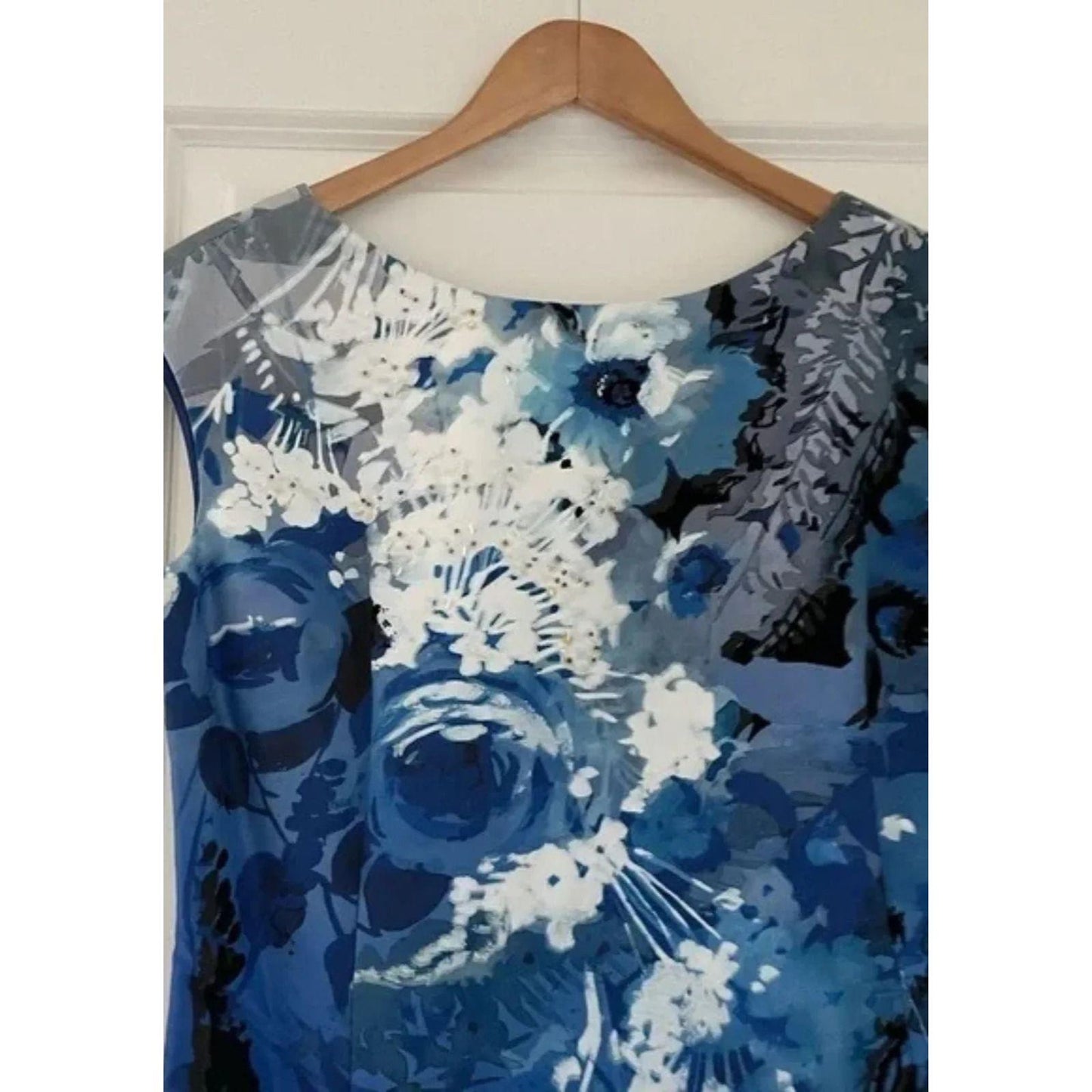 Blue floral dress on a wooden hanger against a white wall