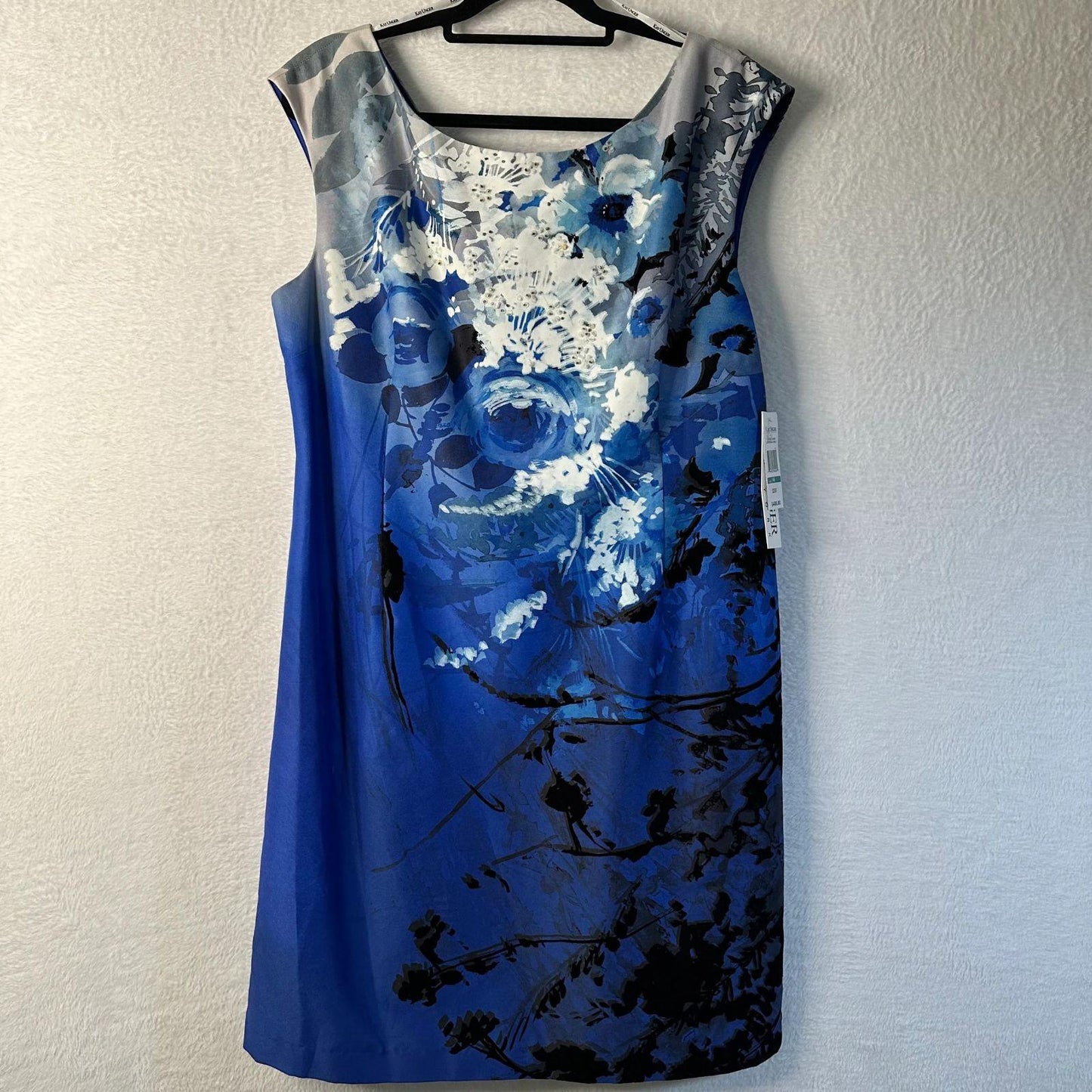 Blue floral dress on a hanger against a white wall