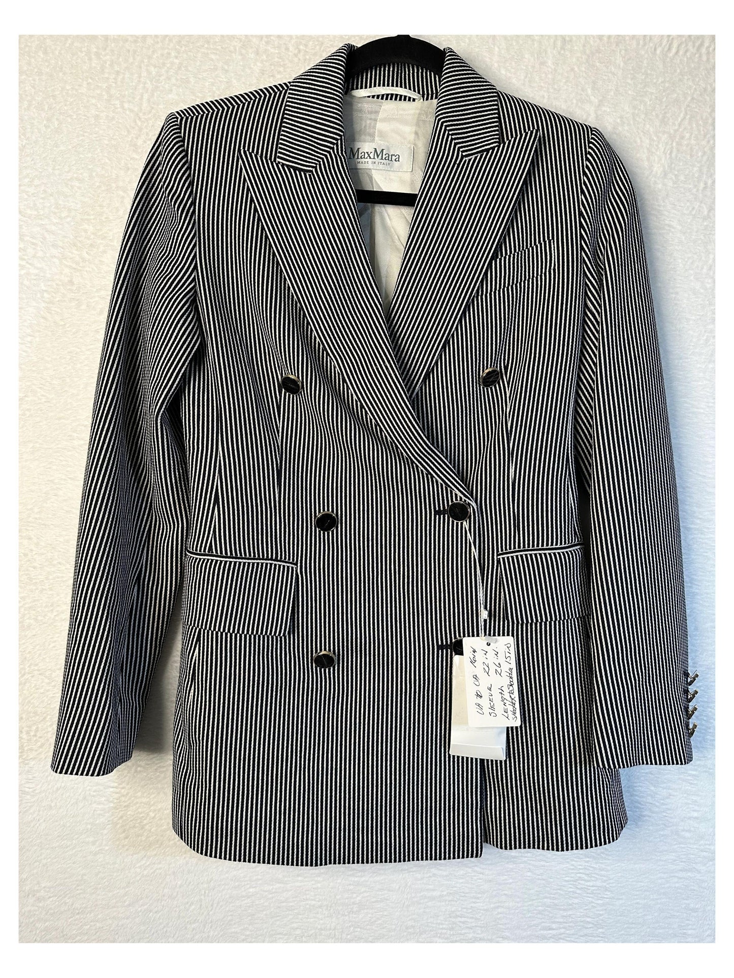 Black and white striped blazer with a tag on a light background