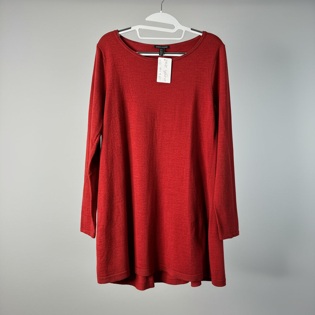 Red long-sleeve a-line tunic sweater on a hanger against a white wooden panel background