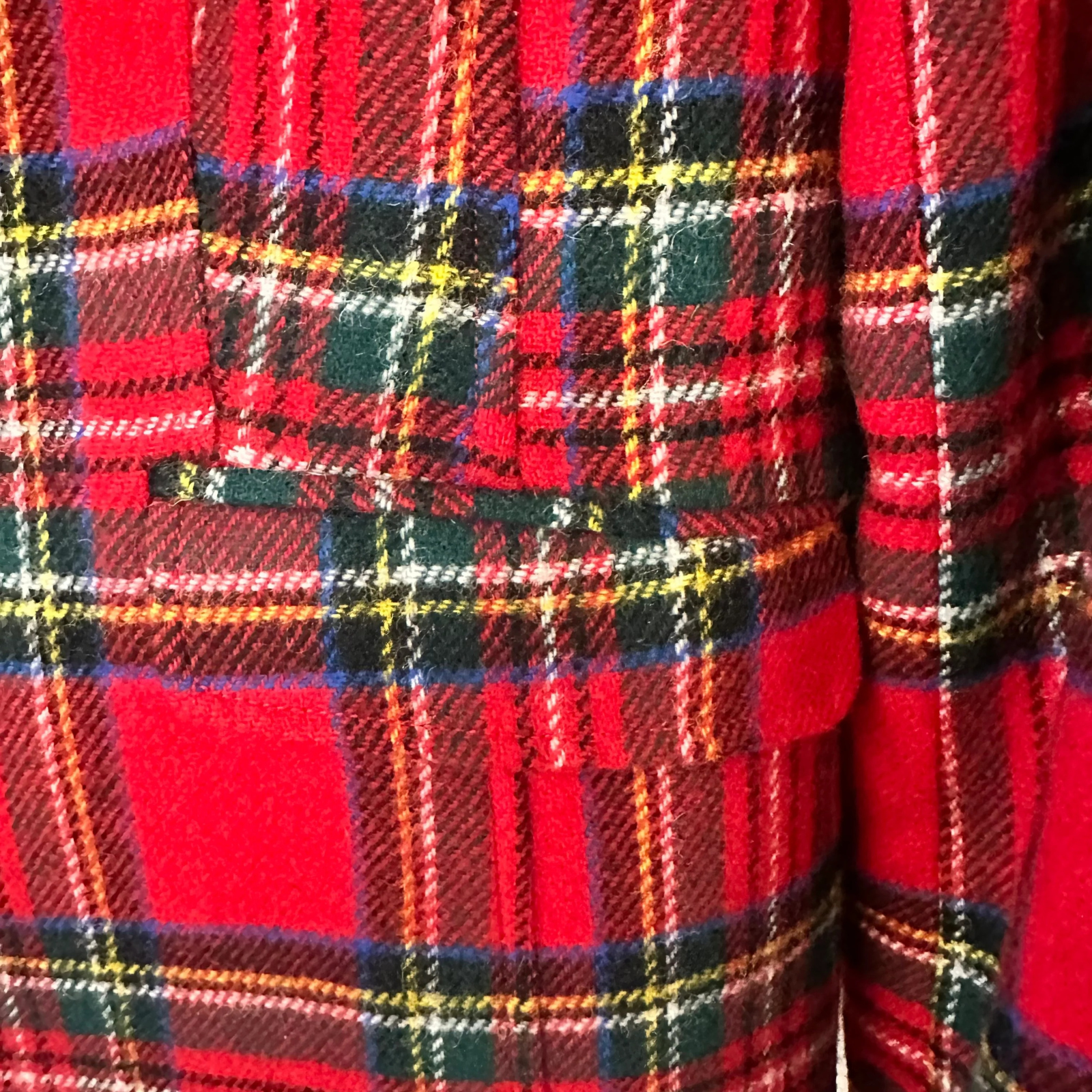 Close-up of red plaid fabric with a pattern of black, yellow, and green lines.