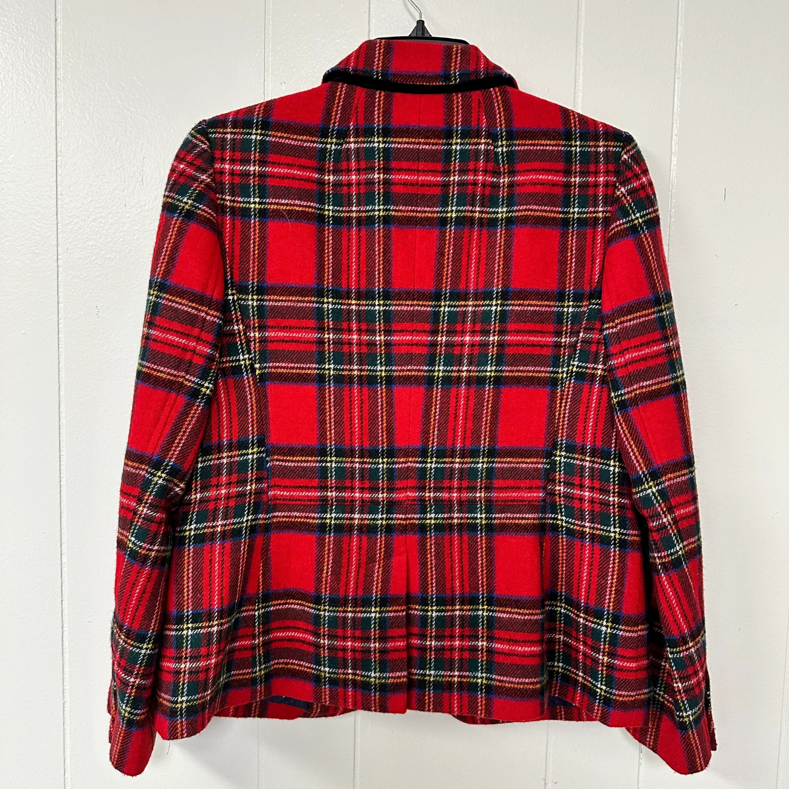 Plaid blazer back view on a hanger against a white wooden background