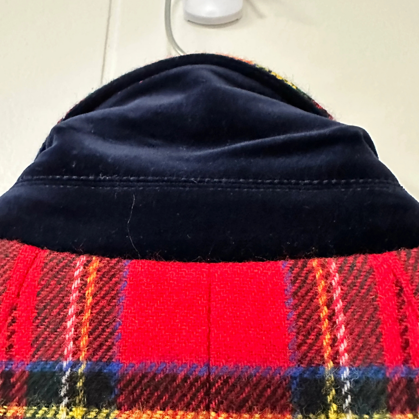 Close-up of a plaid fabric with a dark blue border on a light background