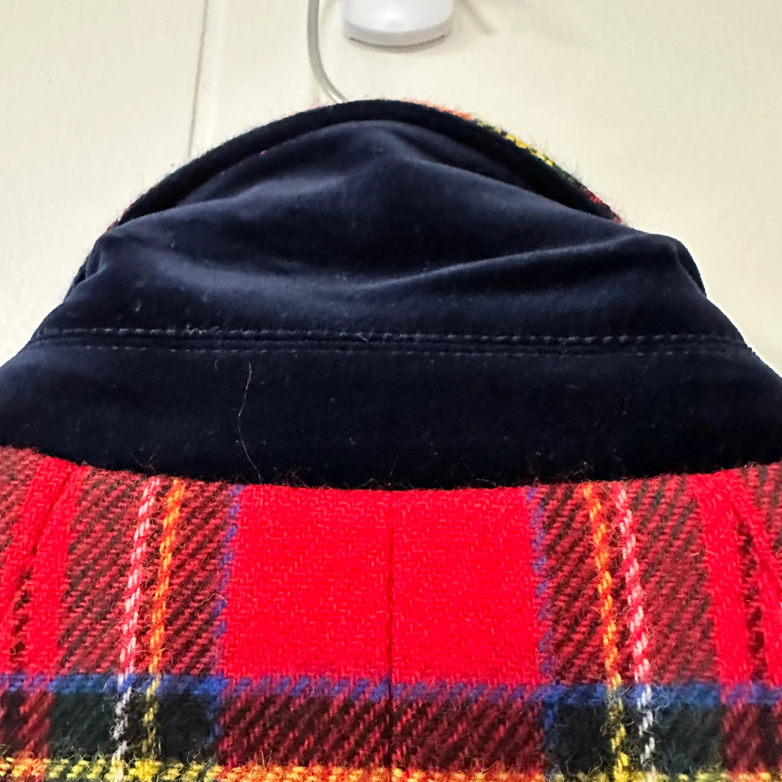 Close-up of a plaid fabric with a dark blue border on a light background