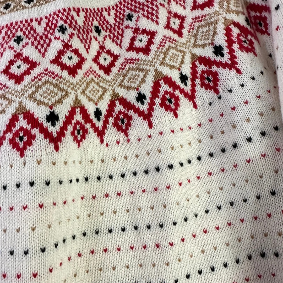 Close-up of a knitted fabric with red, black, and beige pattern on a white background