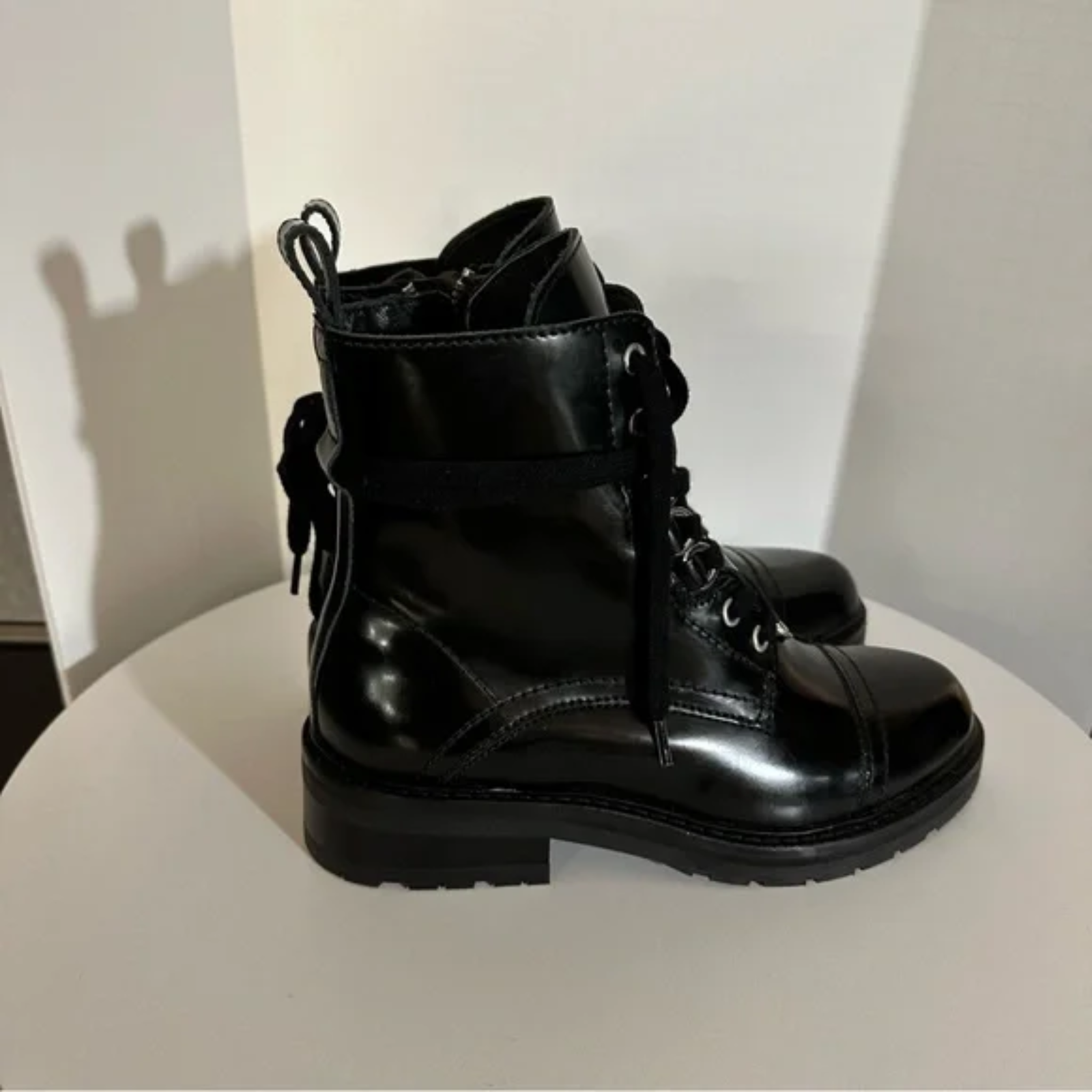 Black leather boots on a white surface with a neutral background