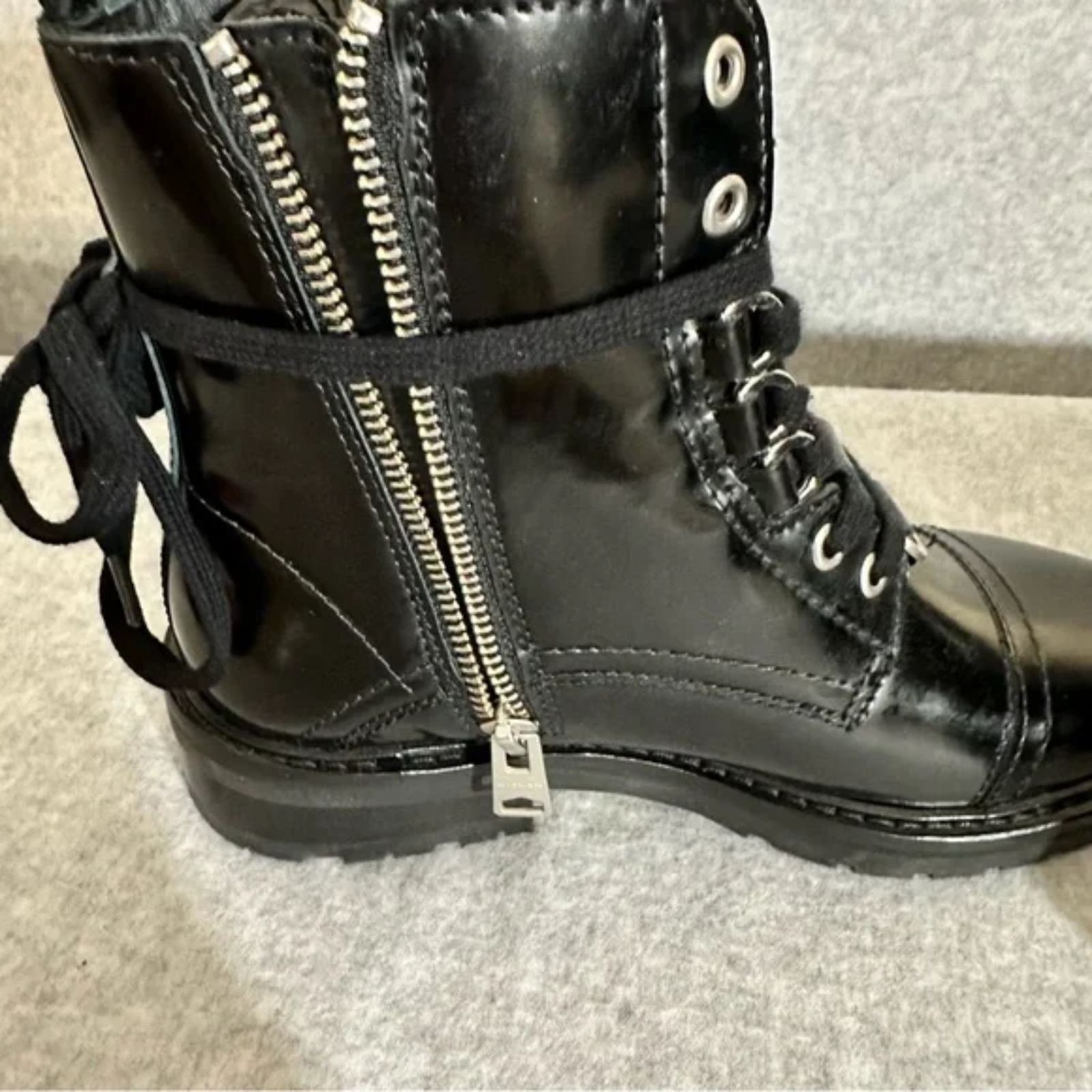 Black combat boots with zippers on a neutral background
